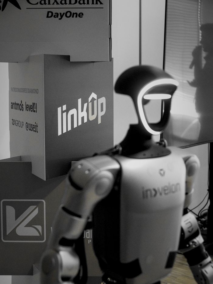 Robot humanoide junto a la torre de patrocinadores