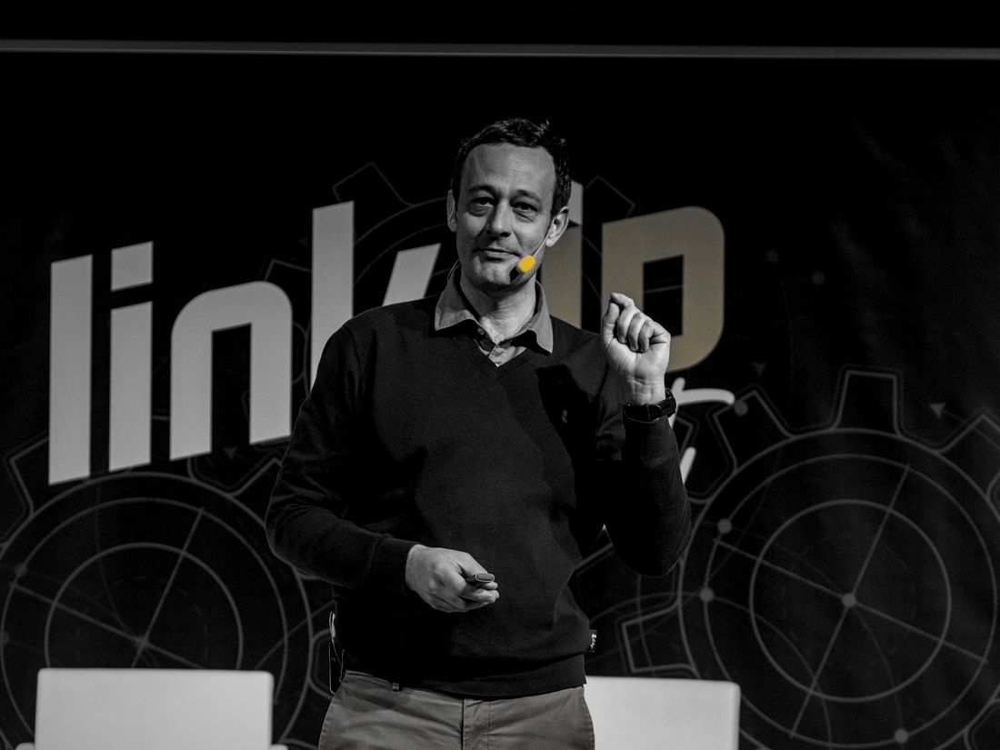 Ponente en el escenario del Link Up Fest, con la marca de fondo