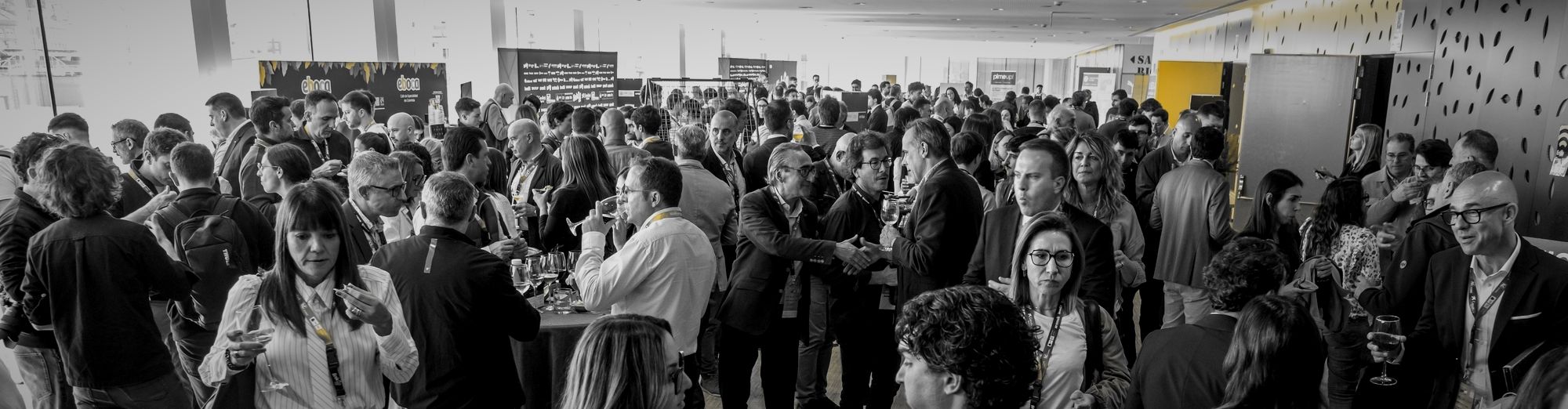 Asistentes haciendo networking en el Link Up Fest, en blanco y negro con las acreditaciones en ámbar